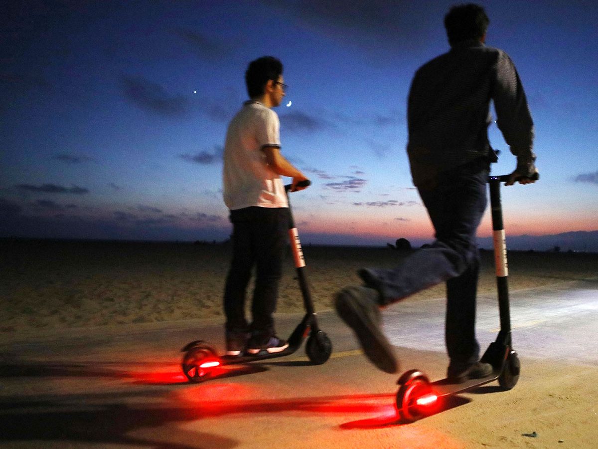 People ride shared dockless electric scooters along Venice Beach on August 13, 2018 in Los Angeles, California.
