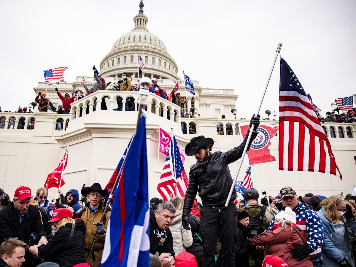people standing in front of the Washington capital building holding flags and protesting