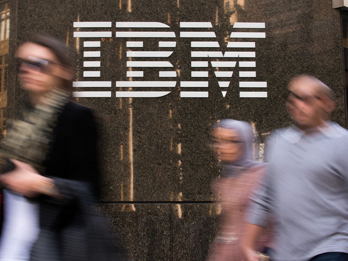 People walk in a blur past an IBM sign