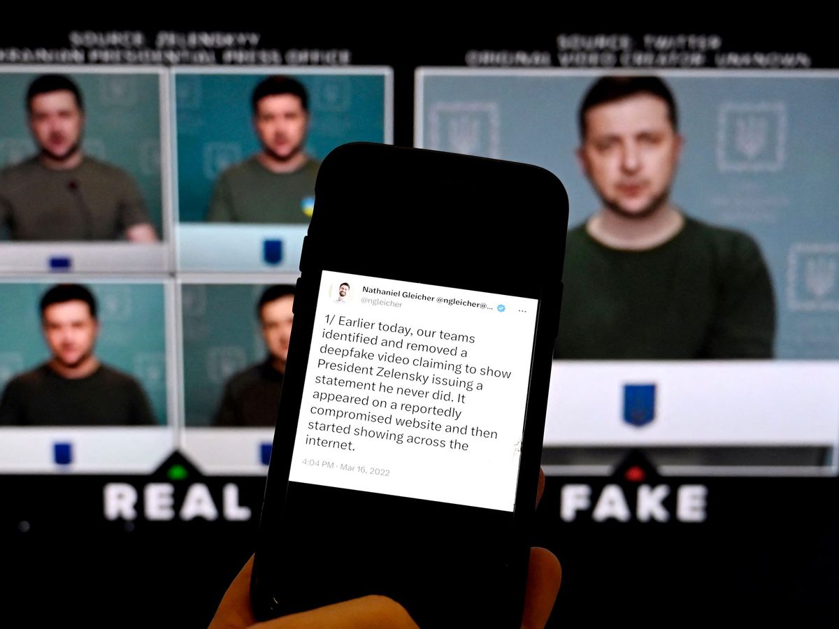 person holding a smartphone with text on the screen and a computer screen in the background with different images of a man