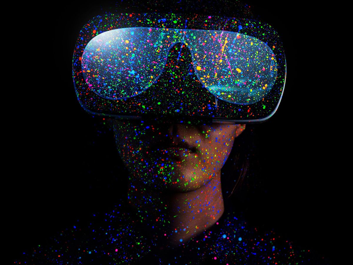person wearing virtual reality goggles with different colored paint splattered all over them against a black background