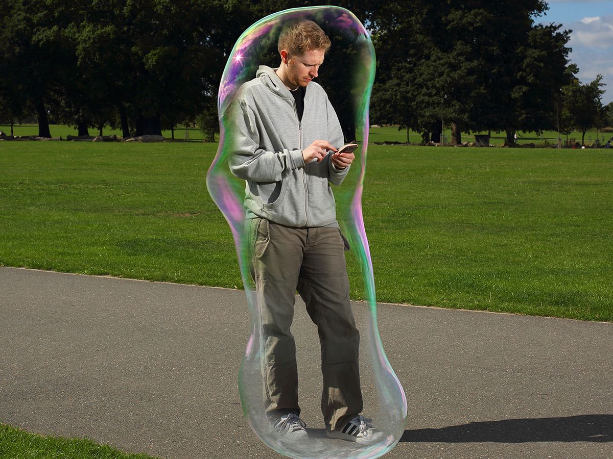 Photo-illustration of a man looking at a phone, walking within his own private bubble.