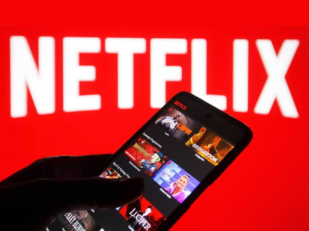 Photo illustration of the Netflix logo with Netflix displayed on a mobile phone.