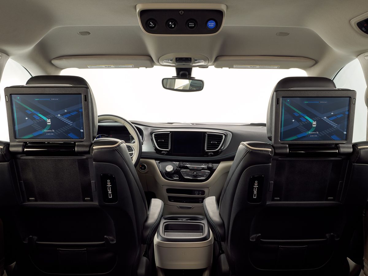 Photo inside one of Waymo's Chrysler Pacifica minivans, with no driver, and a display showing the car's progression on the rear of the front passenger seat.
