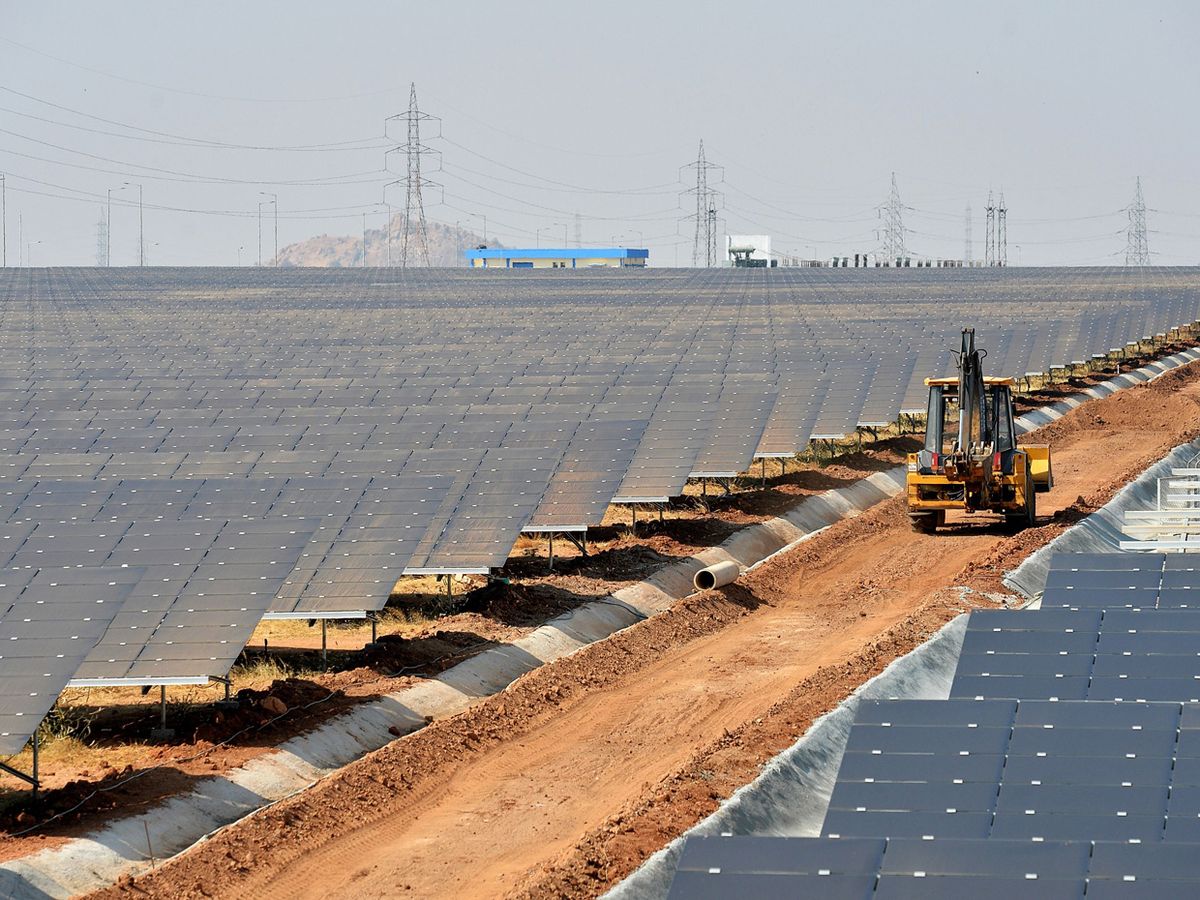 Photo of a construction vehicle driving in a solar panel farm.