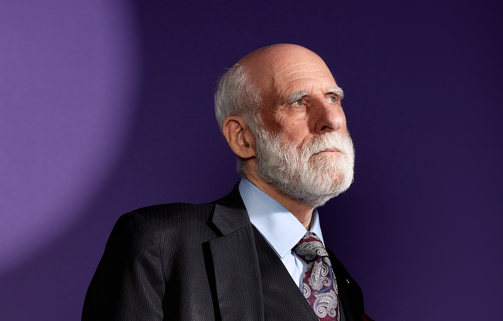 Photo of a man in a suit and tie on a purple background.