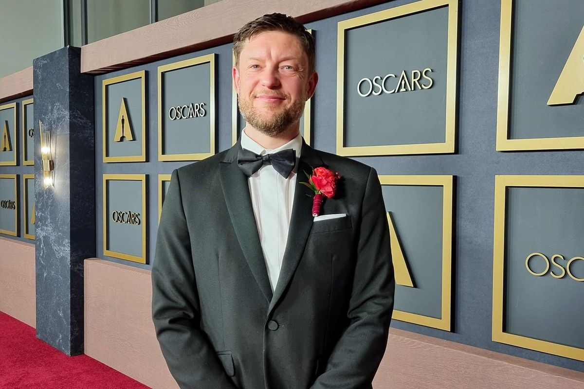 Photo of a man in a tuxedo standing at the Oscars.