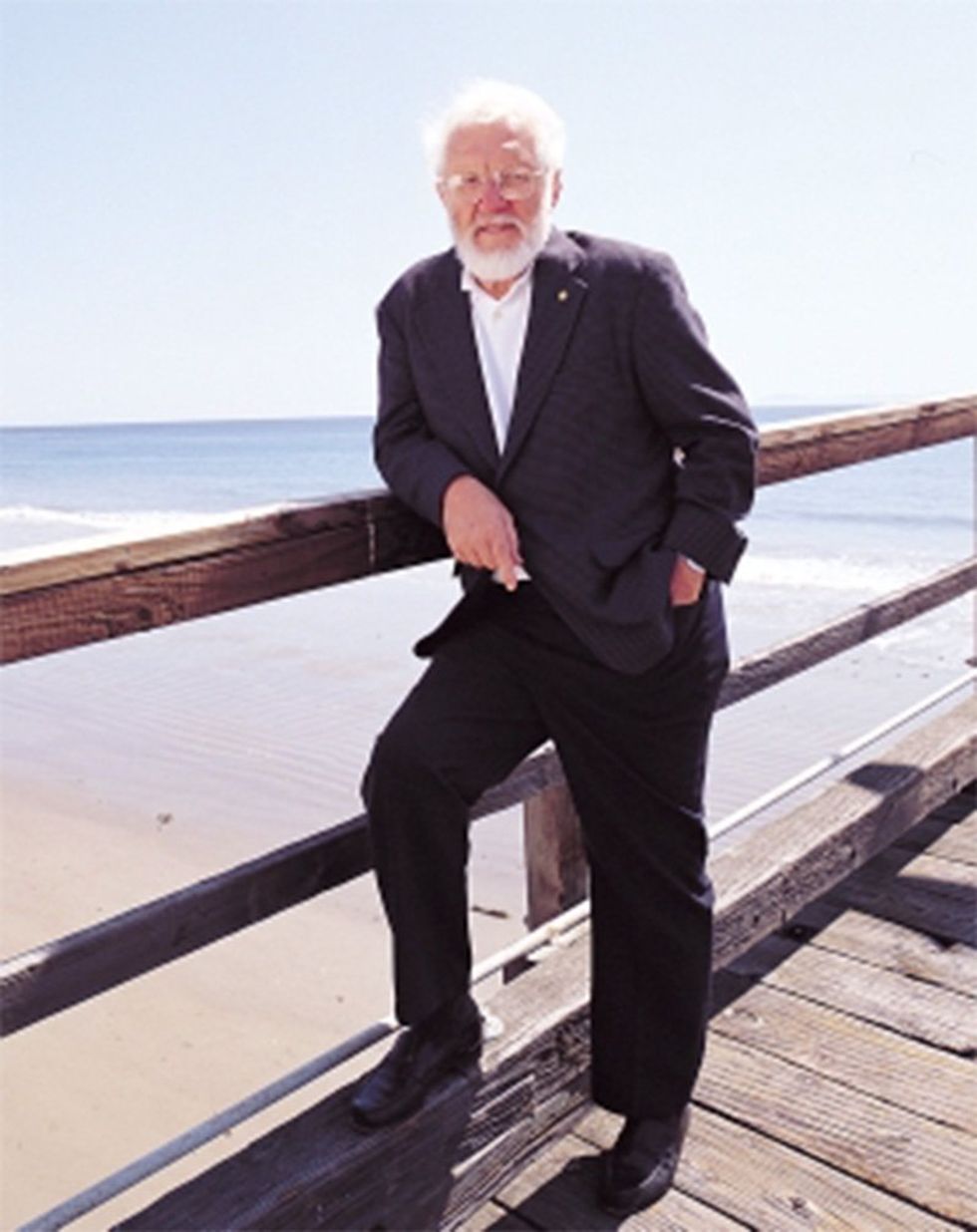 Photo of a man on a pier by a beach.