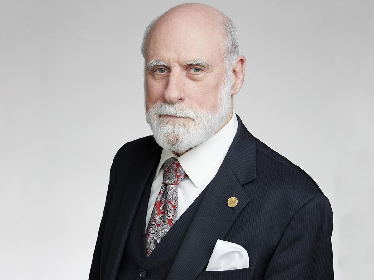 Photo of a man with a white beard in a dark suit.  