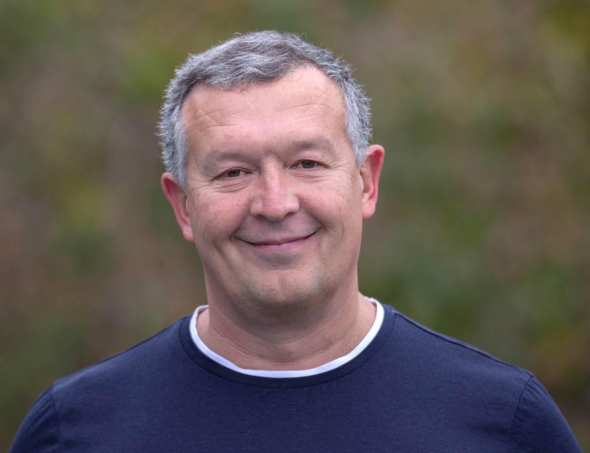 Photo of a smiling man in a blue sweatshirt