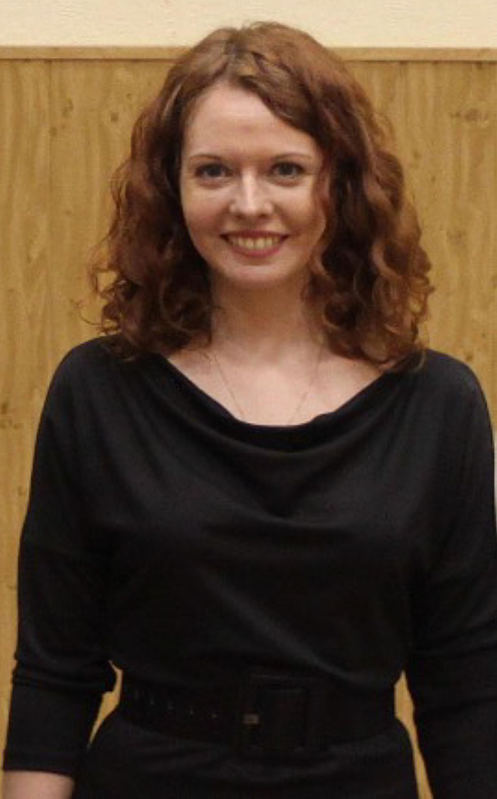 Photo of a smiling red-haired woman in a black dress