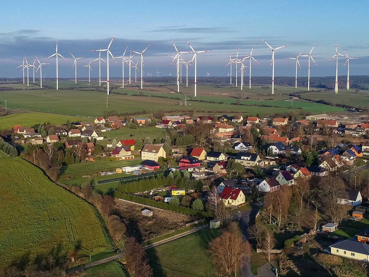 Photo of a village with windmills in the background.