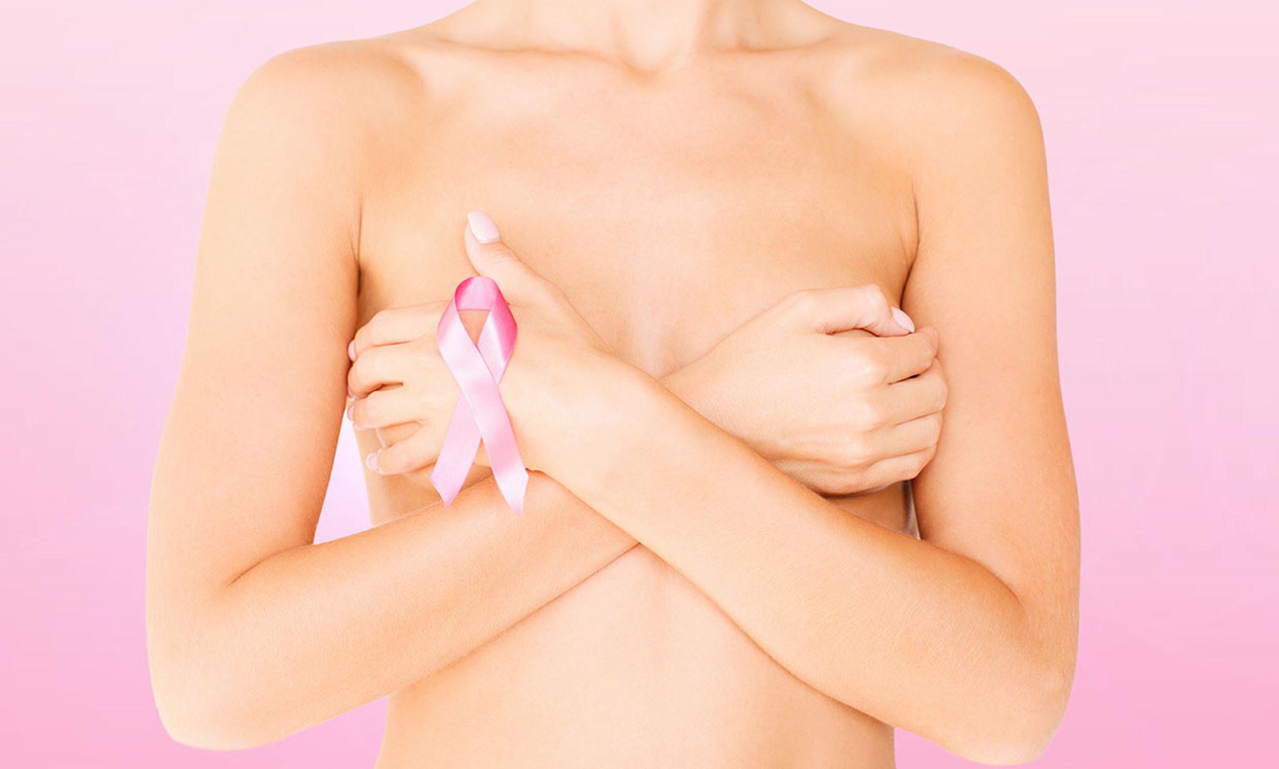 Photo of a woman with a breast cancer ribbon, covering her breasts.
