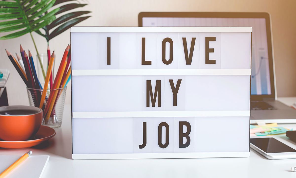 Photo of a work desk with text on light box saying “I love my job”