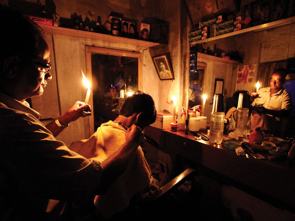 Photo of barber in the eastern city of Kolkata working by candlelight.