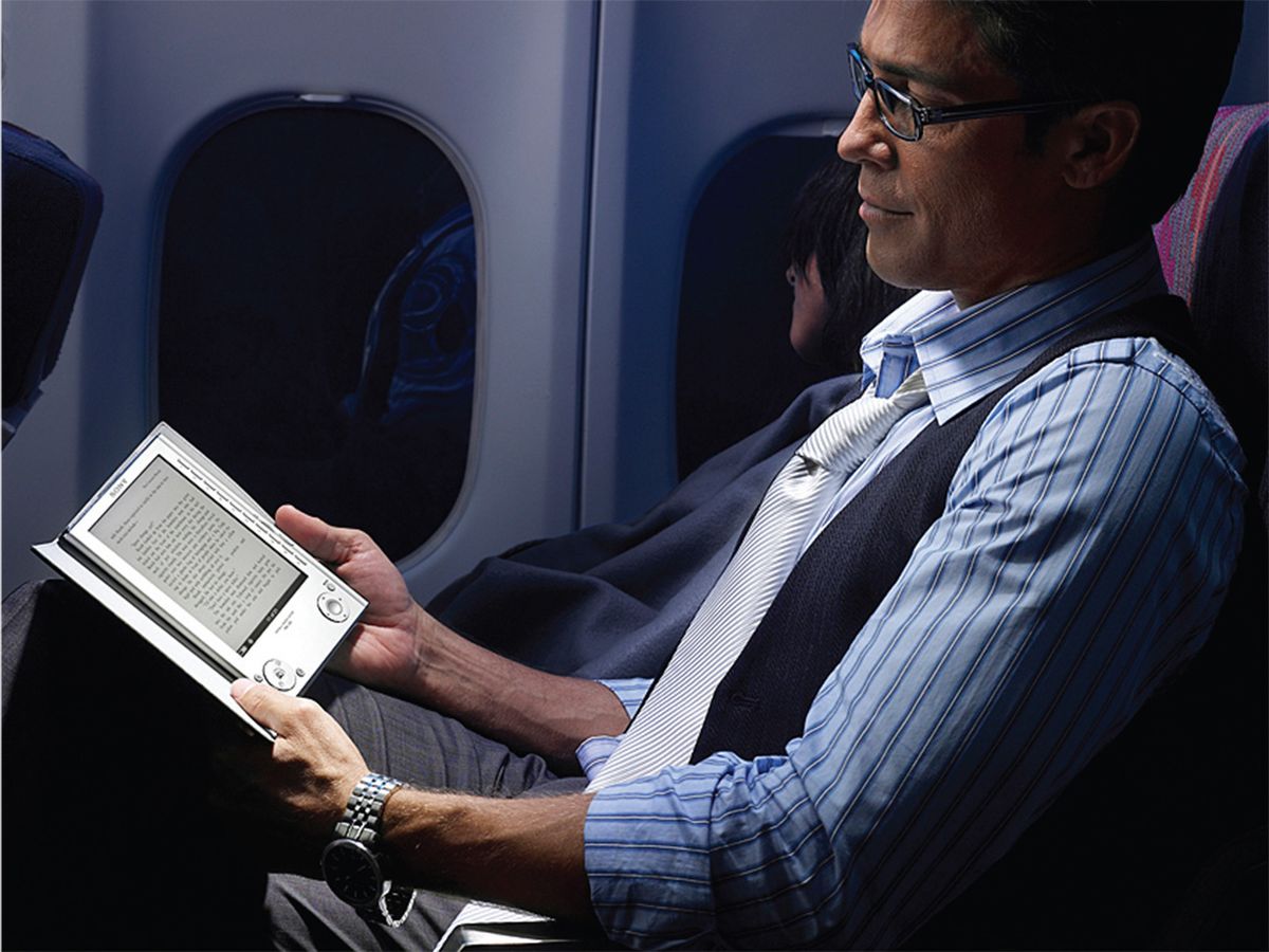 Photo of man reading a tablet in an airplane.