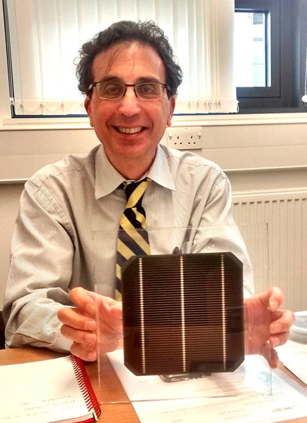 Photo of Oxford PV chief technology officer Chris Case holding a tandem silicon solar cell wafer featuring a perovskite coating.