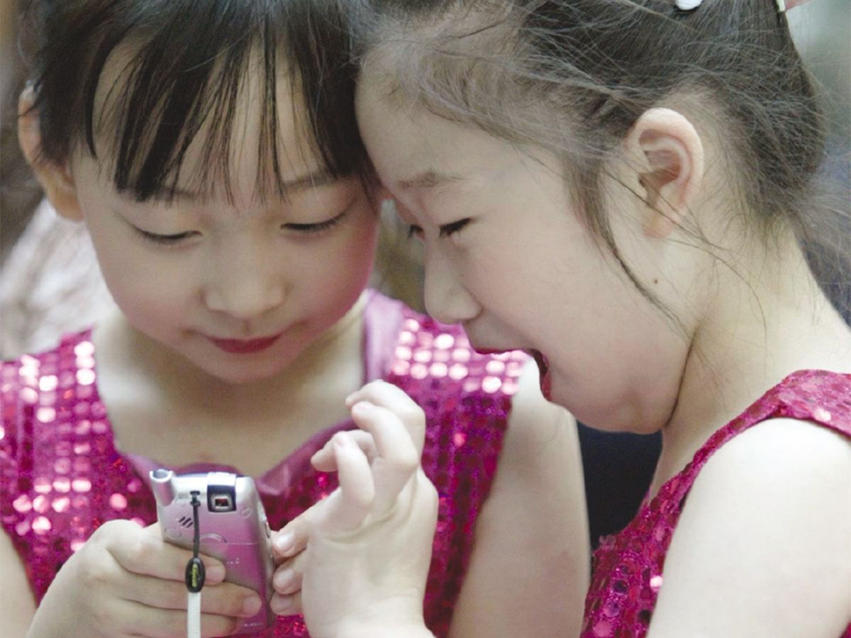 Photo of two kindergartners playing with a cellphone.