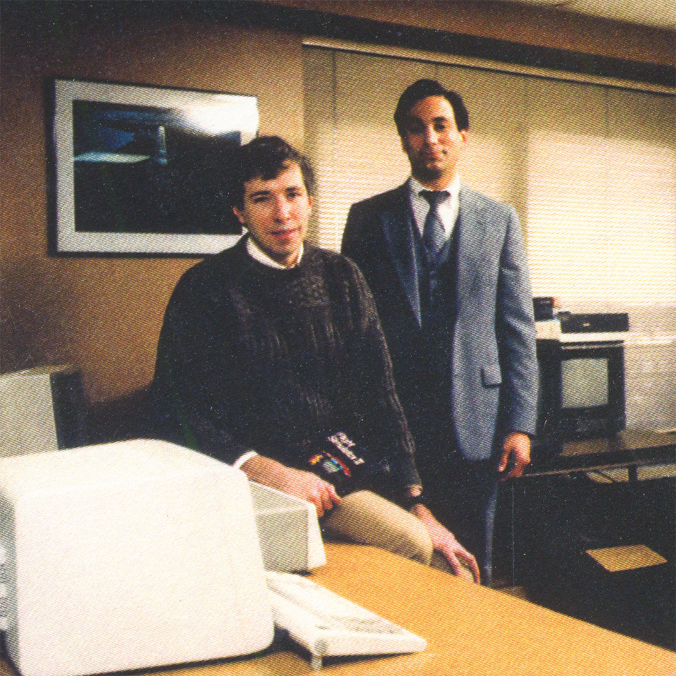 Photo of two men near a laptop