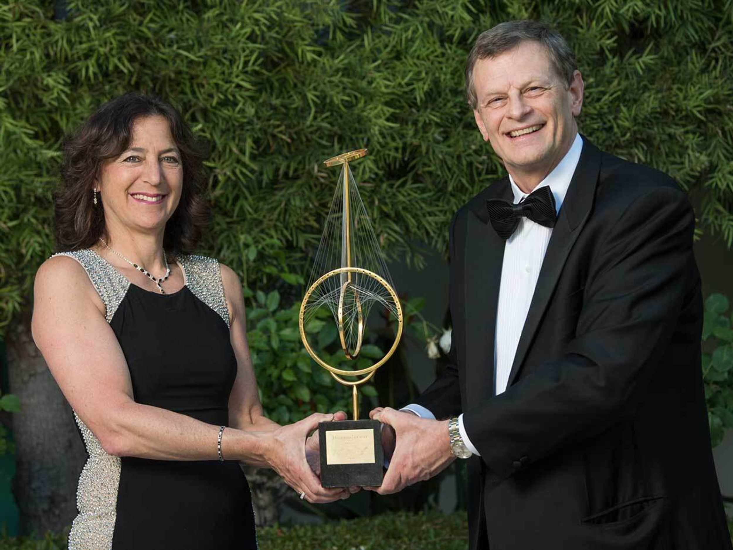Photo of two people holding an award.