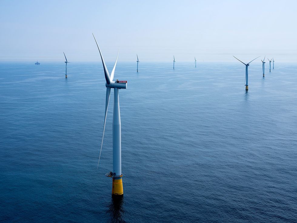 Photo of wind turbines sitting on yellow bases in the ocean.