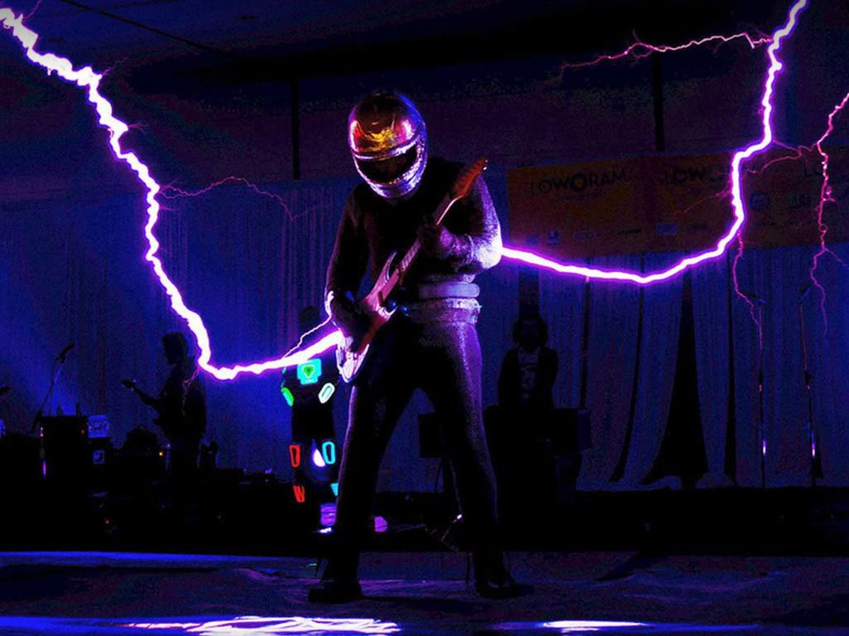 Photo showing that ArcAttack makes its own Tesla coils to produce giant sparks for live performances—and a wearable Faraday cage to perform in.