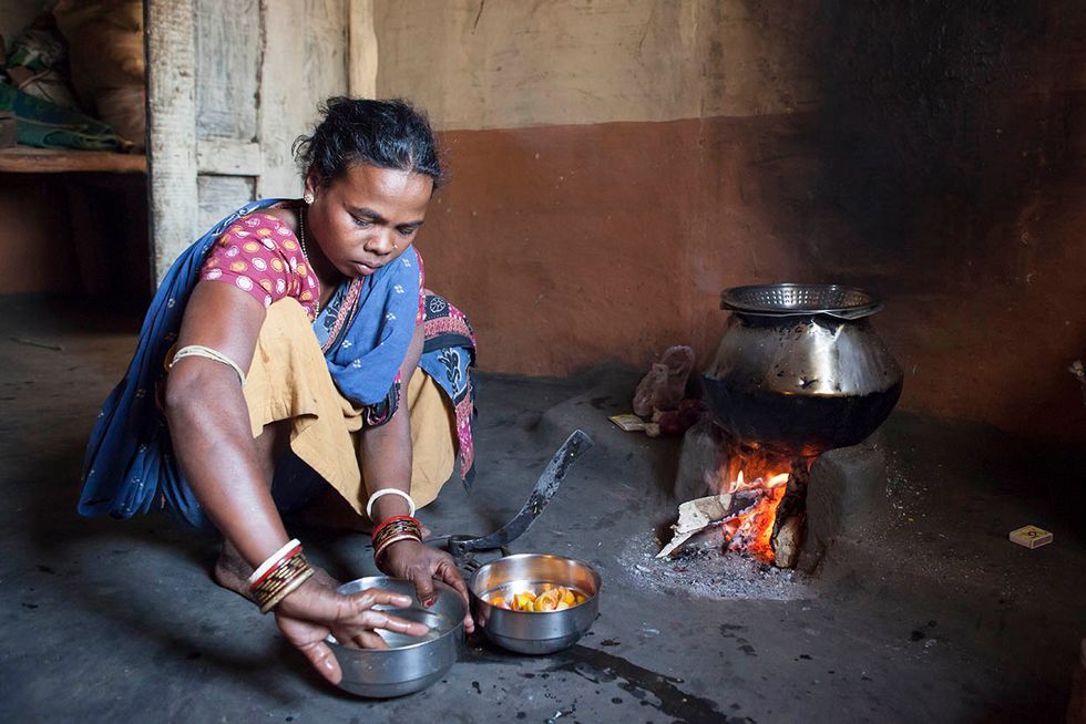 Photo showing woman with traditional cookstove.
