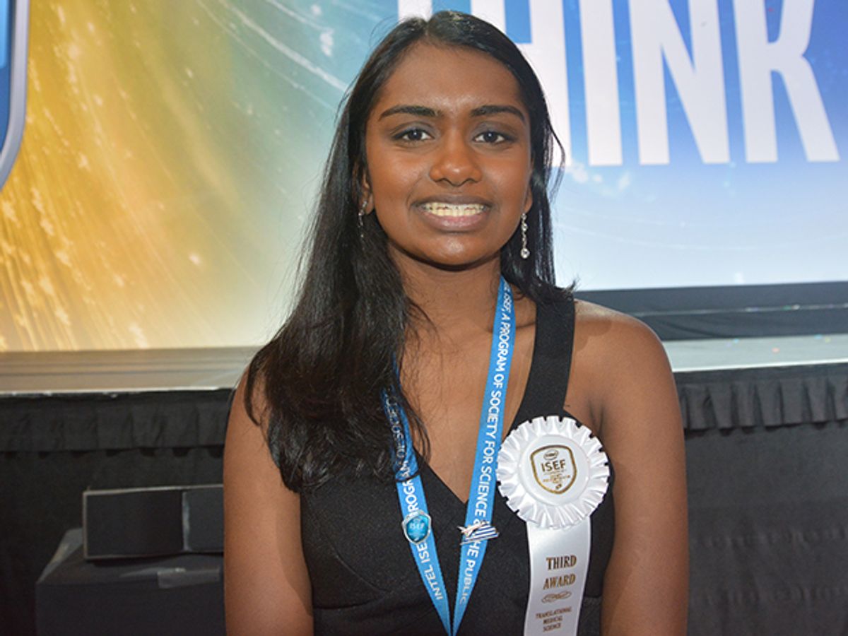 Photo shows a smiling teenage girl with an award ribbon from a science fair.