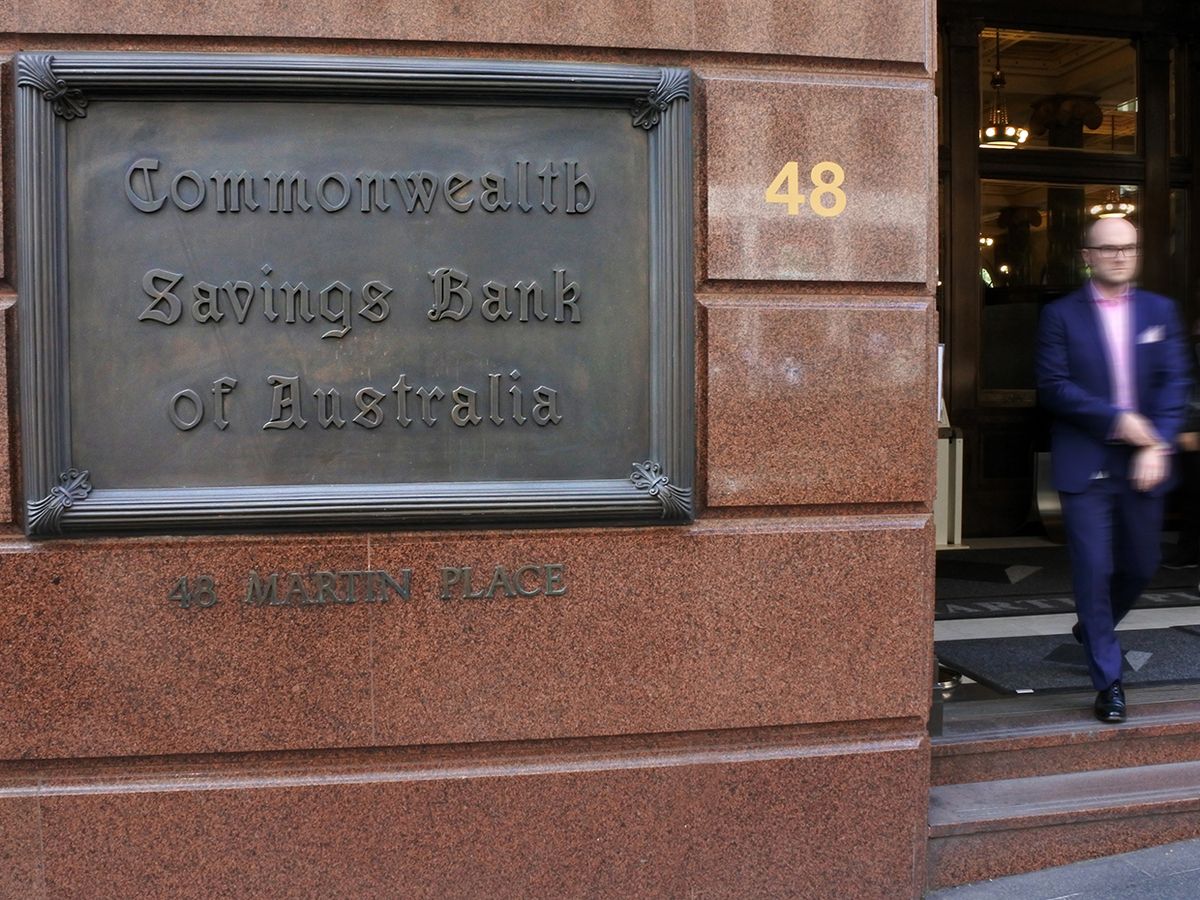 Photograph of a man exiting a building labelled with a Commonwealth Bank of Australia sign in Sydney, New South Wales, Australia.