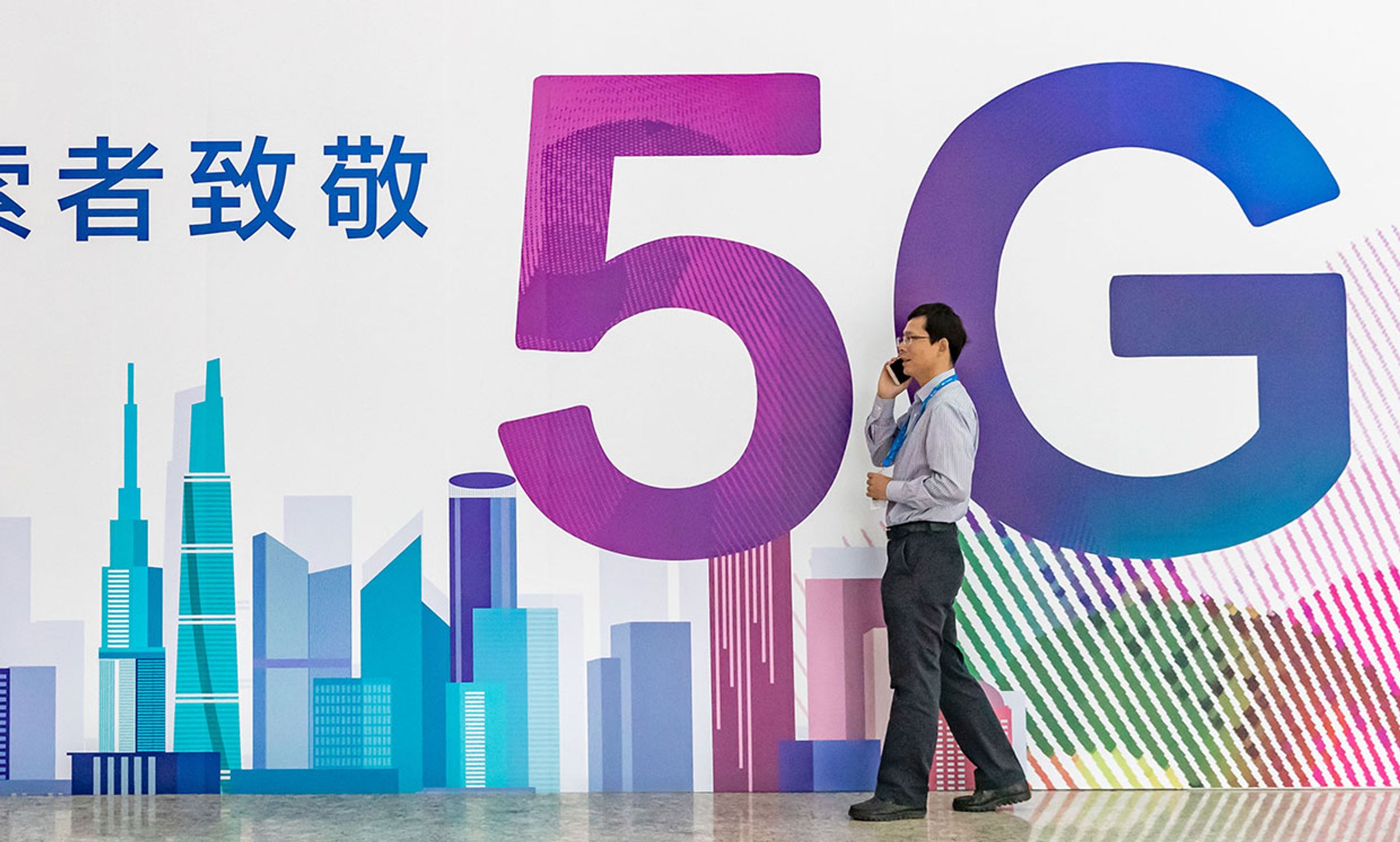 Photograph of a man in front of a 5G sign with Chinese characters on it.