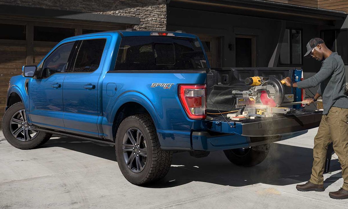 Photograph of a man using a saw plugged into Ford's new Pro Power Onboard mobile generator for its new F-150 pickup.