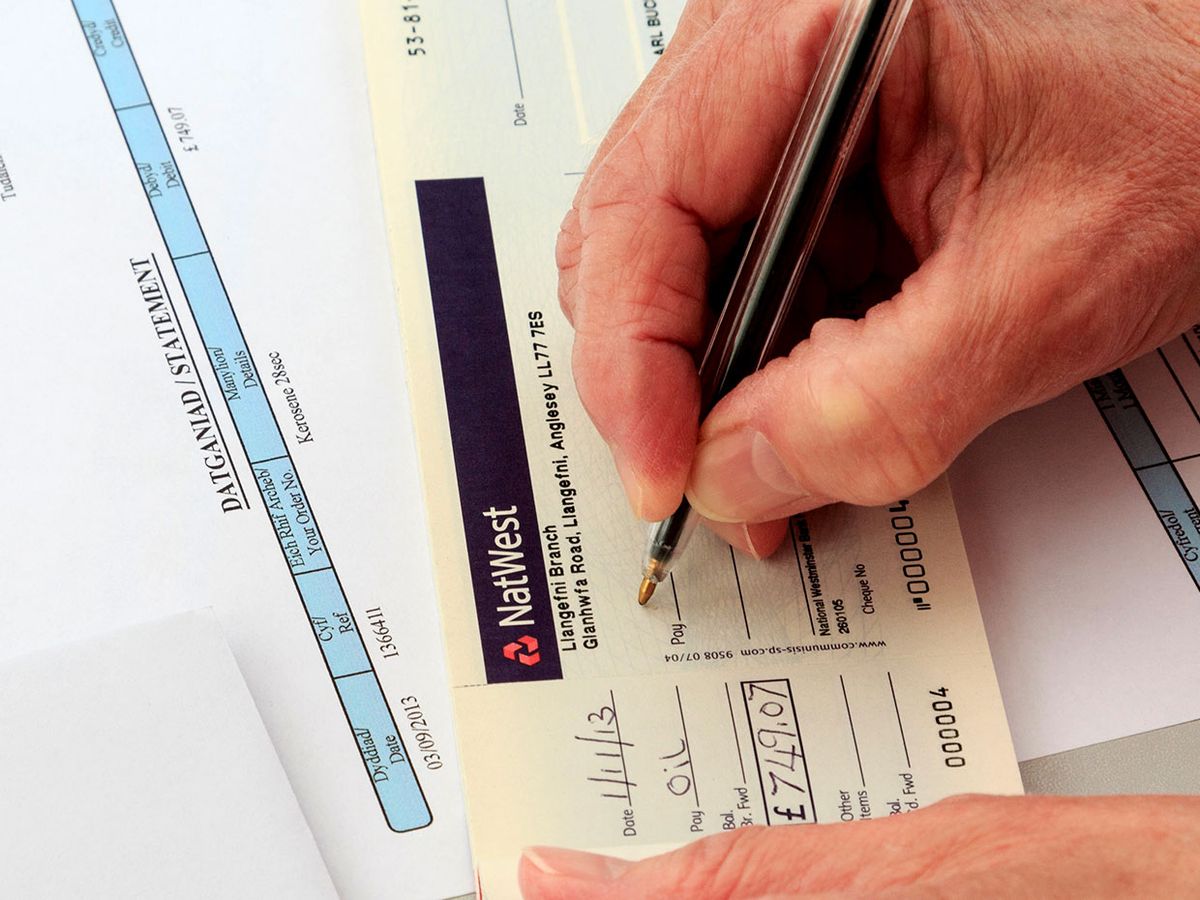 Photograph of a senior in the UK signing a check.