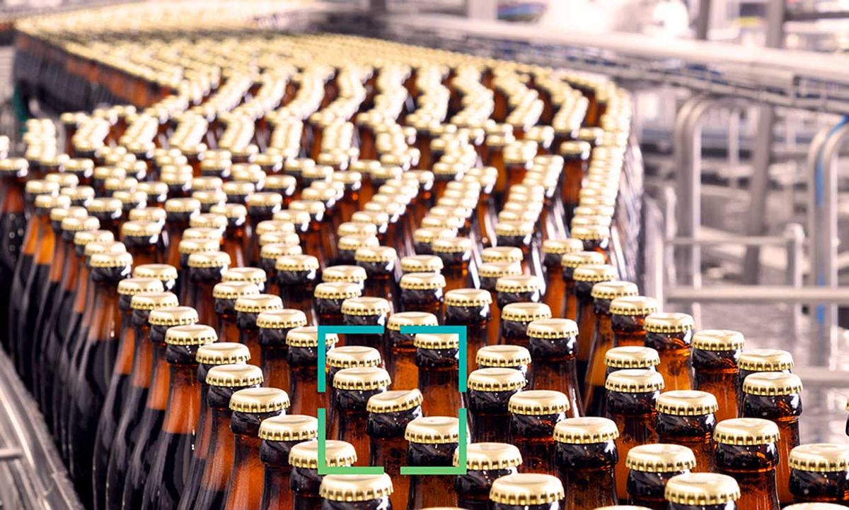 Photograph of bottles on a manufacturing line with a square over a bottle that a system would note as defective