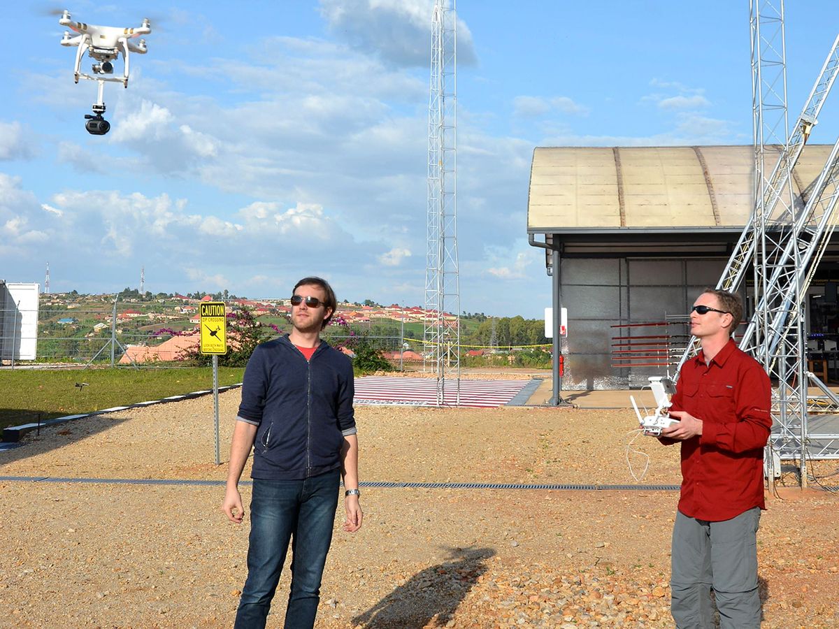Photograph of Michael Koziol (left) and Evan Ackerman operating a drone in the air above them.