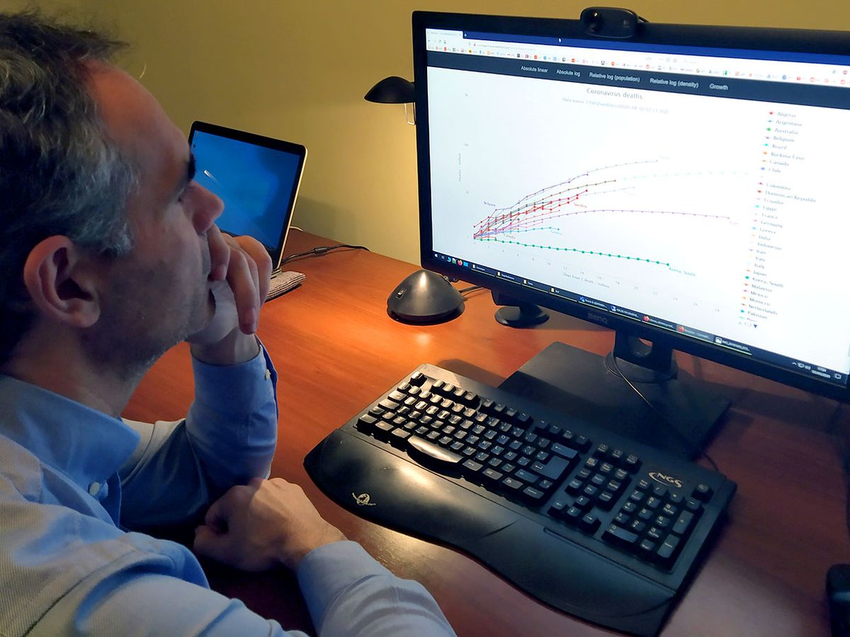 Photograph of Ruben Usamentiaga Fernandez studies the website he has created to track COVID-19 related deaths around the world.