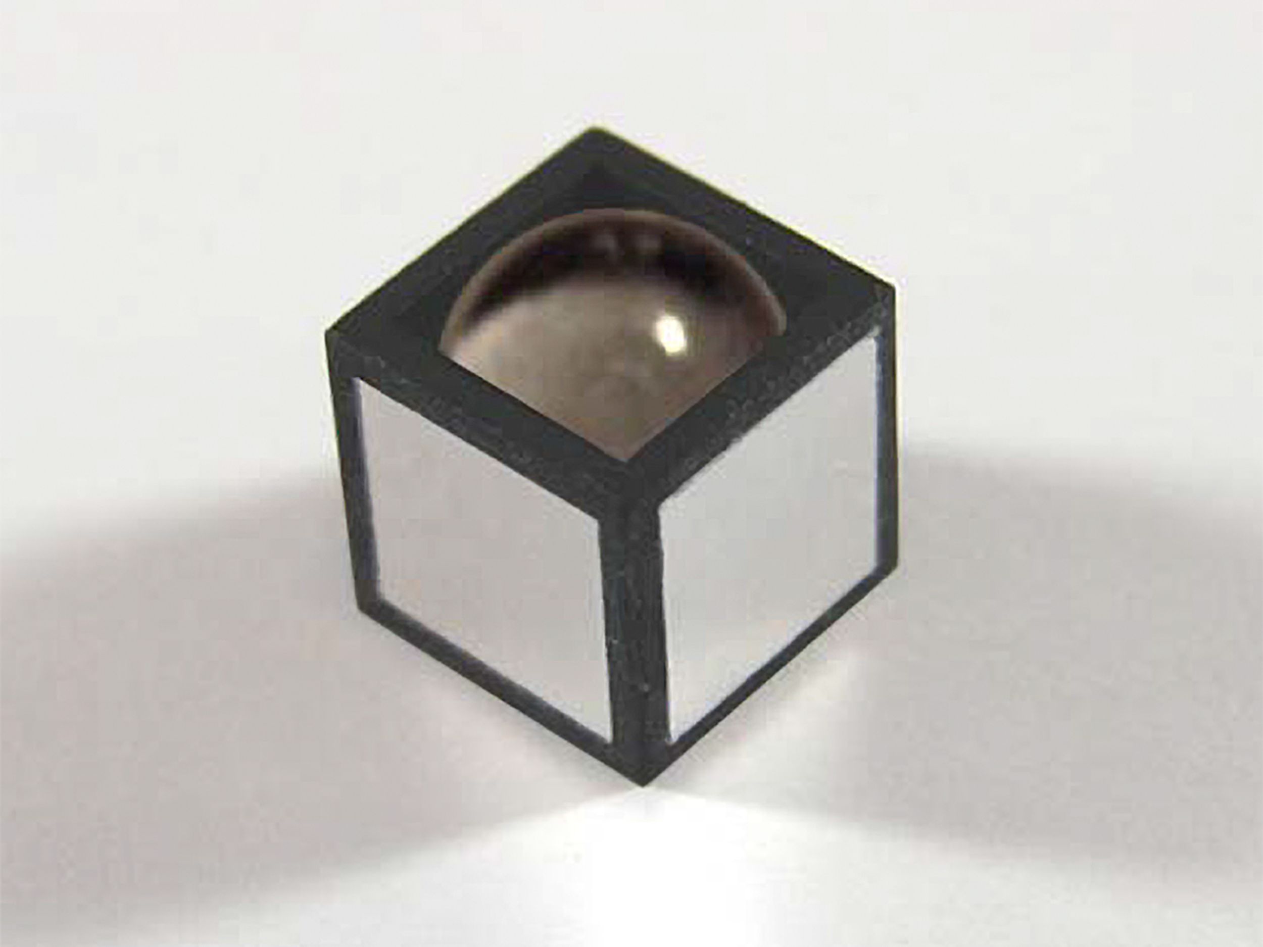 Photograph of the sensor, with the top electrode removed. It looks like a black and white cube with a drop of water bulging from the top. The dimensions are 3 × 3 × 3 mm.