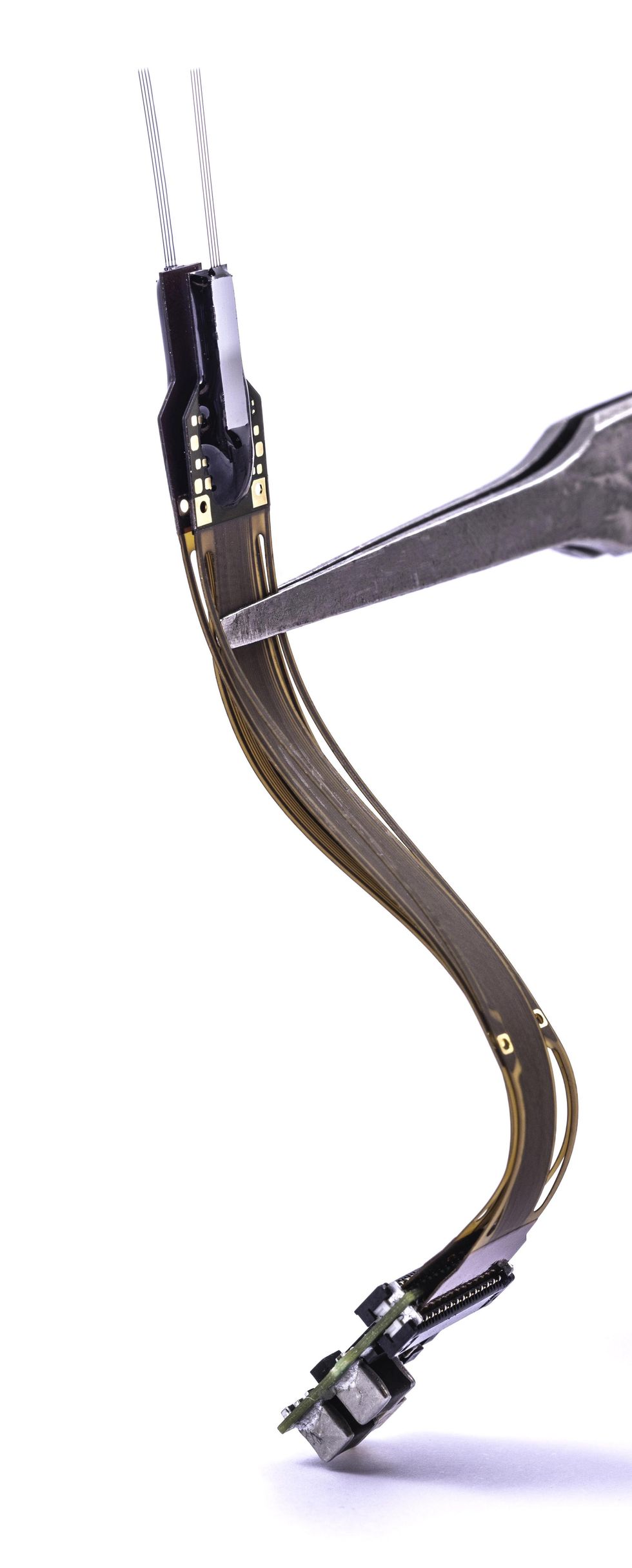 Pliers hold a long and slender electronic device upright. The device has eight delicate wires projecting from its top. 