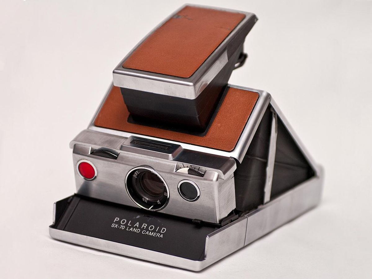 polaroid sx-70 camera, silver with brown leather, open on white surface