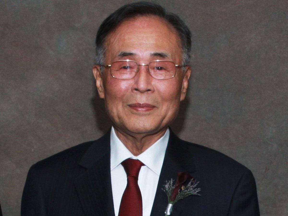 portrait of a man wearing a suit and glasses looking at the camera against a gray background