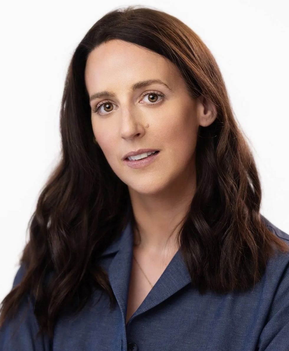Portrait of a woman with long dark hair and a blue button up shirt.