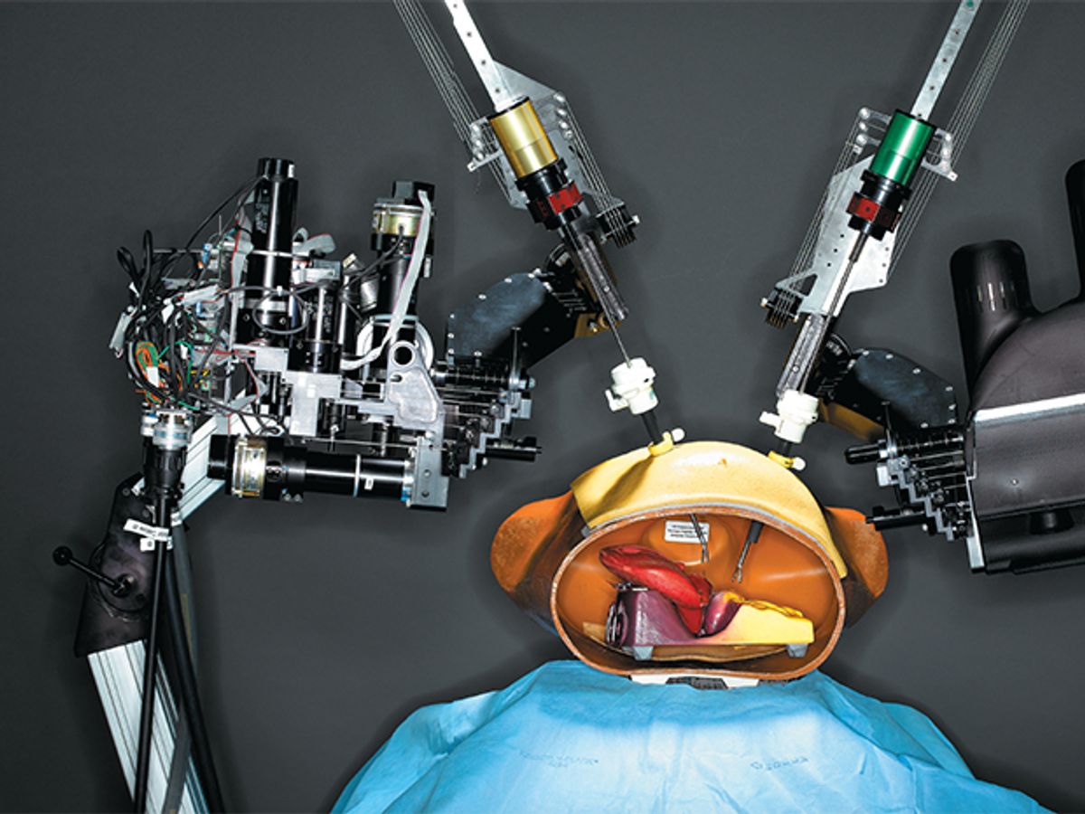 remote-controlled two-armed surgical robot “operates” on a plastic and rubber anatomical model of a human torso.