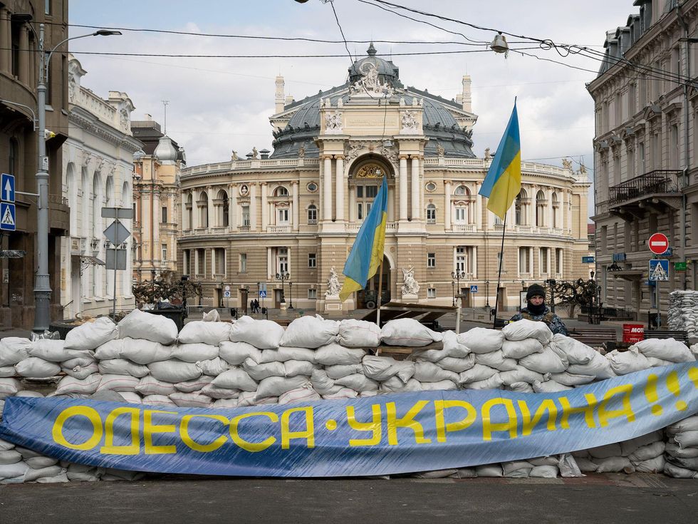Sandbags and Ukrainian flags sit in front of a majestic building