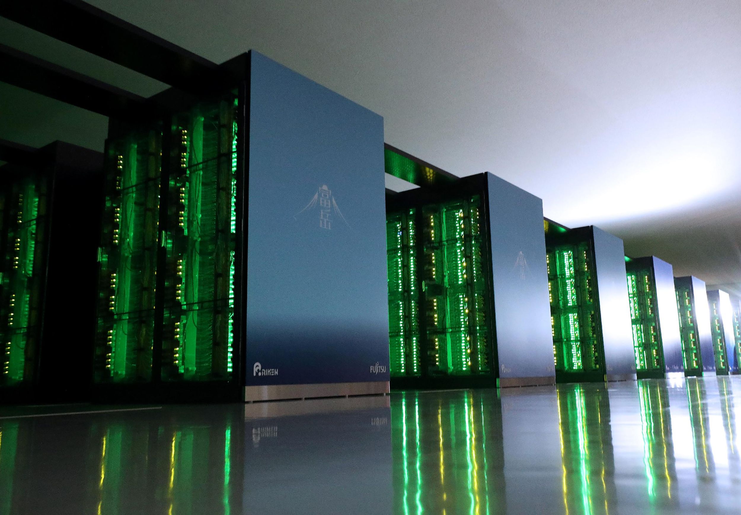 Several cabinets of a supercomputer glow green with lights