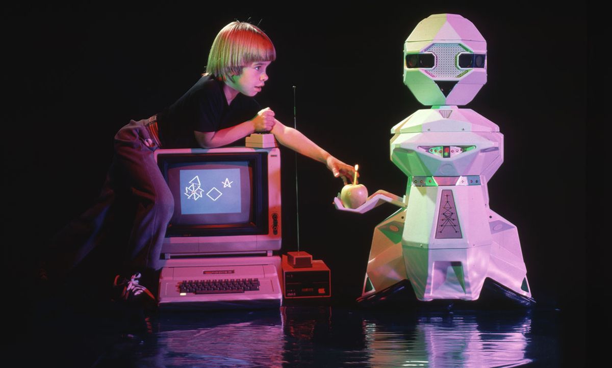 Shawn Melville uses a computer joystick to operate a personal robot. A Topo robot built by Androbot brings him an apple.