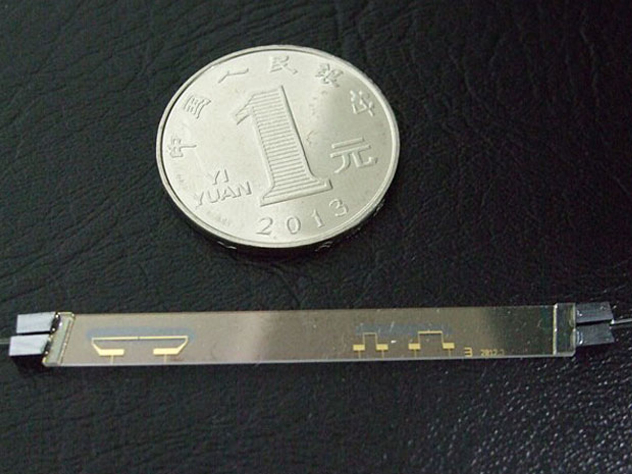 Small coin next to photonic chip to show scale