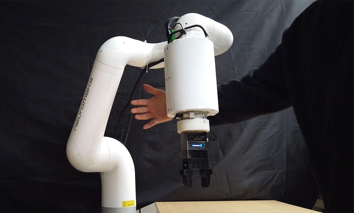 Still image from a video showing a hand near a robotic arm.