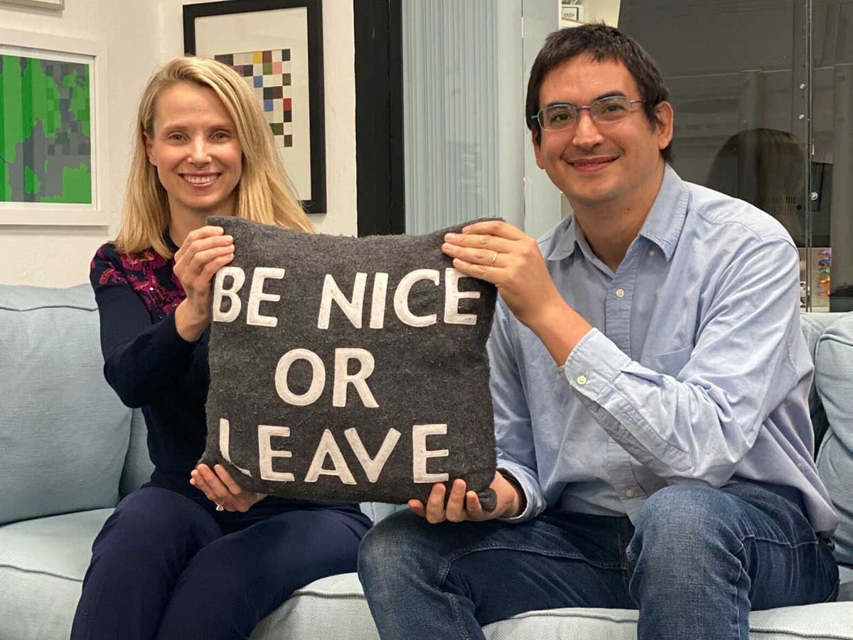 Sunshine founders Marissa Mayer (left) and Enrique Munoz Torres hold a pillow that says "Be nice or leave".