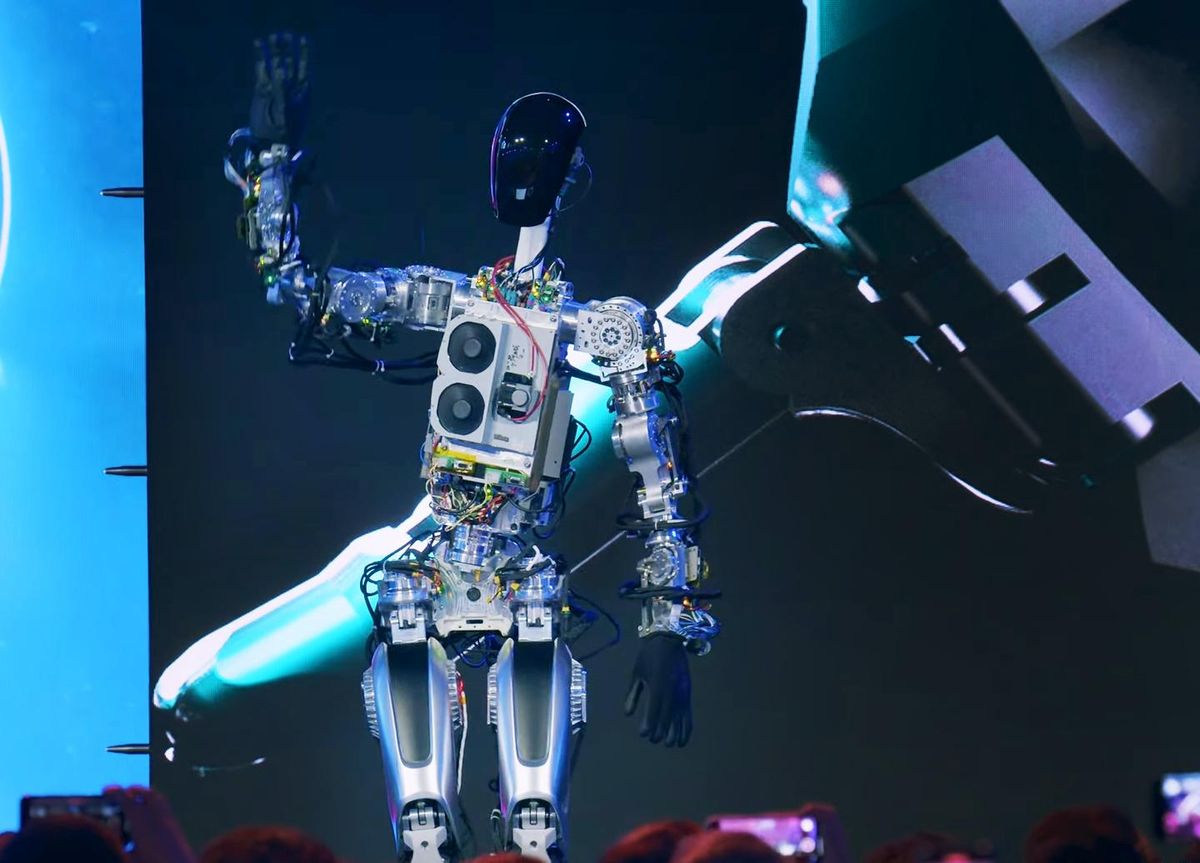 Tesla's Optimus robot waves at audience from the stage.