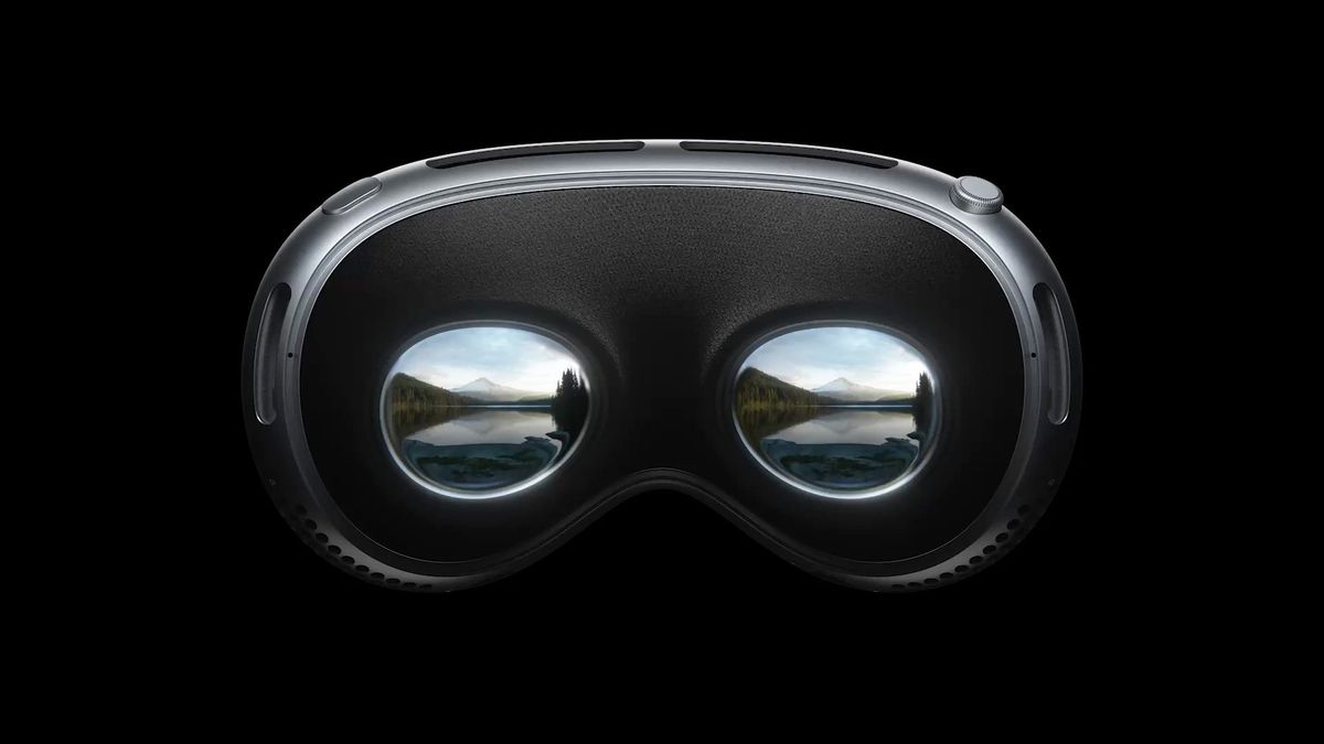 The Apple Vision Pro headset turned towards the user. A display inside the headset shows two mirrored images of a mountain landscape.