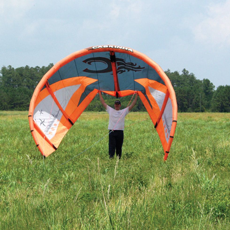The author holds one of the off-the-shelf kiteboarding kites used to test the WindLift generator, waiting for the wind to pick up enough for a good launch.